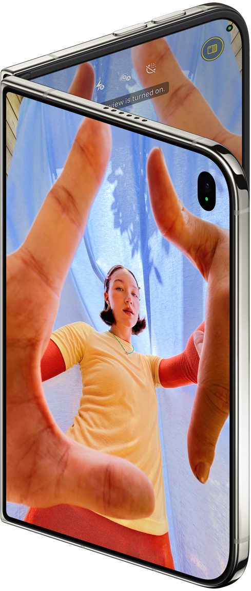 جهاز iPhone Duo، لون أبيض النجوم، مفتوح قليلاً، تطبيق الكاميرا على الشاشة الخارجية مع الكاميرا الأمامية Center Stage، الشاشة الداخلية تعرض مكتبة تطبيق الصور