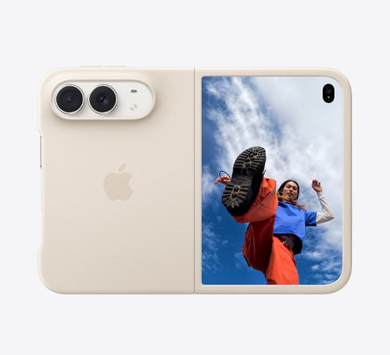 iPhone Duo, color blanco estrella con funda de silicón color arena, posición horizontal, completamente abierto, dos cámaras Fusion en la esquina superior izquierda, la funda cubre la parte posterior y el borde exterior de la pantalla frontal, a la derecha se muestra la pantalla exterior con la imagen de una persona parada bajo un cielo azul lleno de nubes